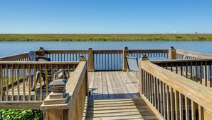 A wooden deck with chairs and a table overlooking a calm body of water. - Lake Okeechobee Dockside Cabin w/ Pool Access (Okeechobee)