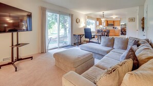 A spacious living room with a large sofa, a flat-screen TV mounted on a stand, and a dining area with a table and chairs. - Jackson Home w/ Fire Pit: Near Parks & Downtown! (Jackson)
