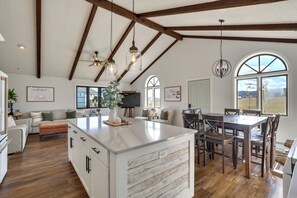 A spacious kitchen with a large island, wooden beams, and a dining area with a table and chairs. - Black Hills, Sturgis Rally Base w/ Trailer Parking (Piedmont)