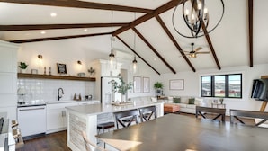 A spacious kitchen with a large island, wooden beams, pendant lighting, and a view of the outdoors. - Mtn Views, Hot Tub + Fire Pit: Black Hills Retreat (Piedmont)