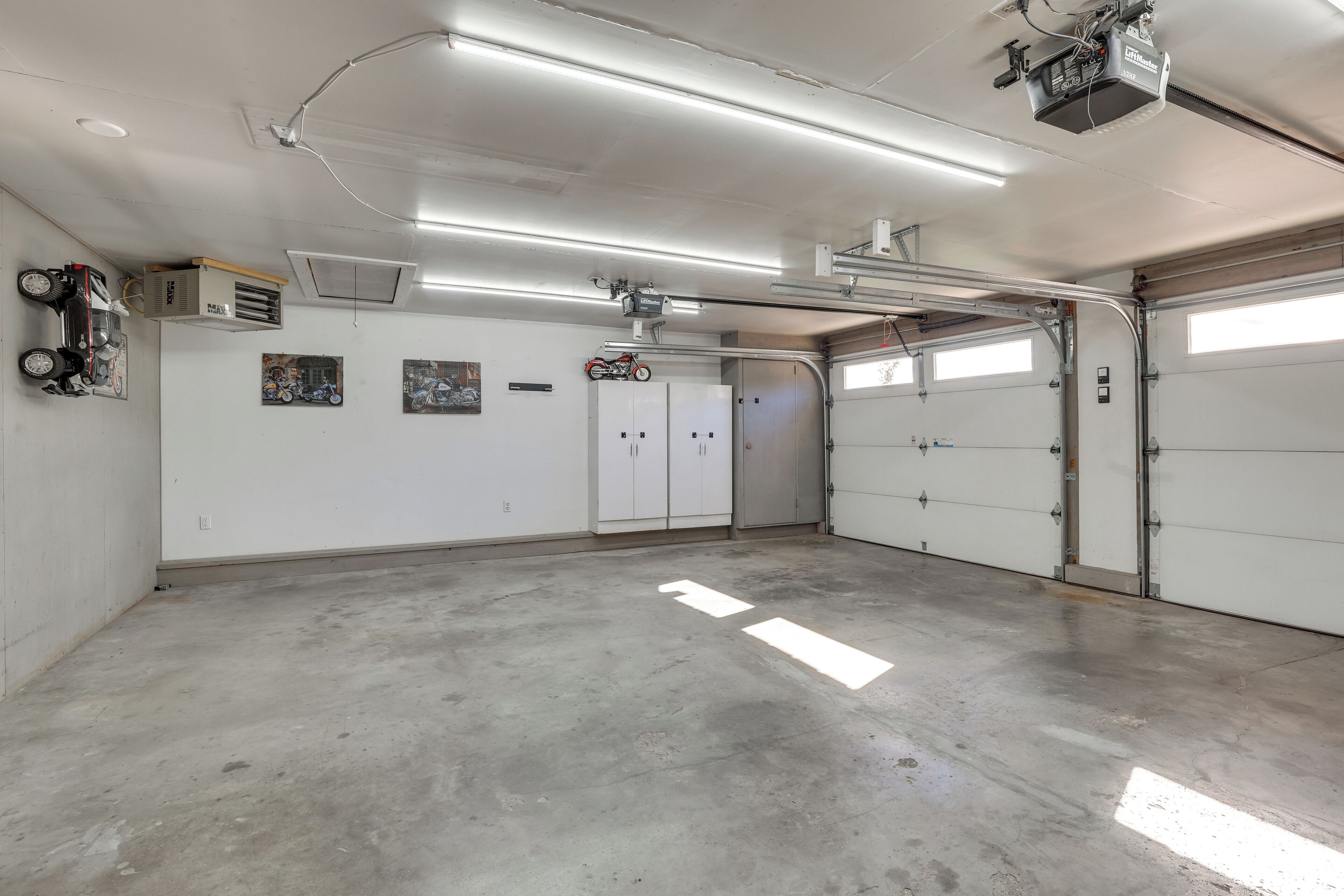 A spacious garage with concrete floors, white walls, and multiple storage cabinets.
