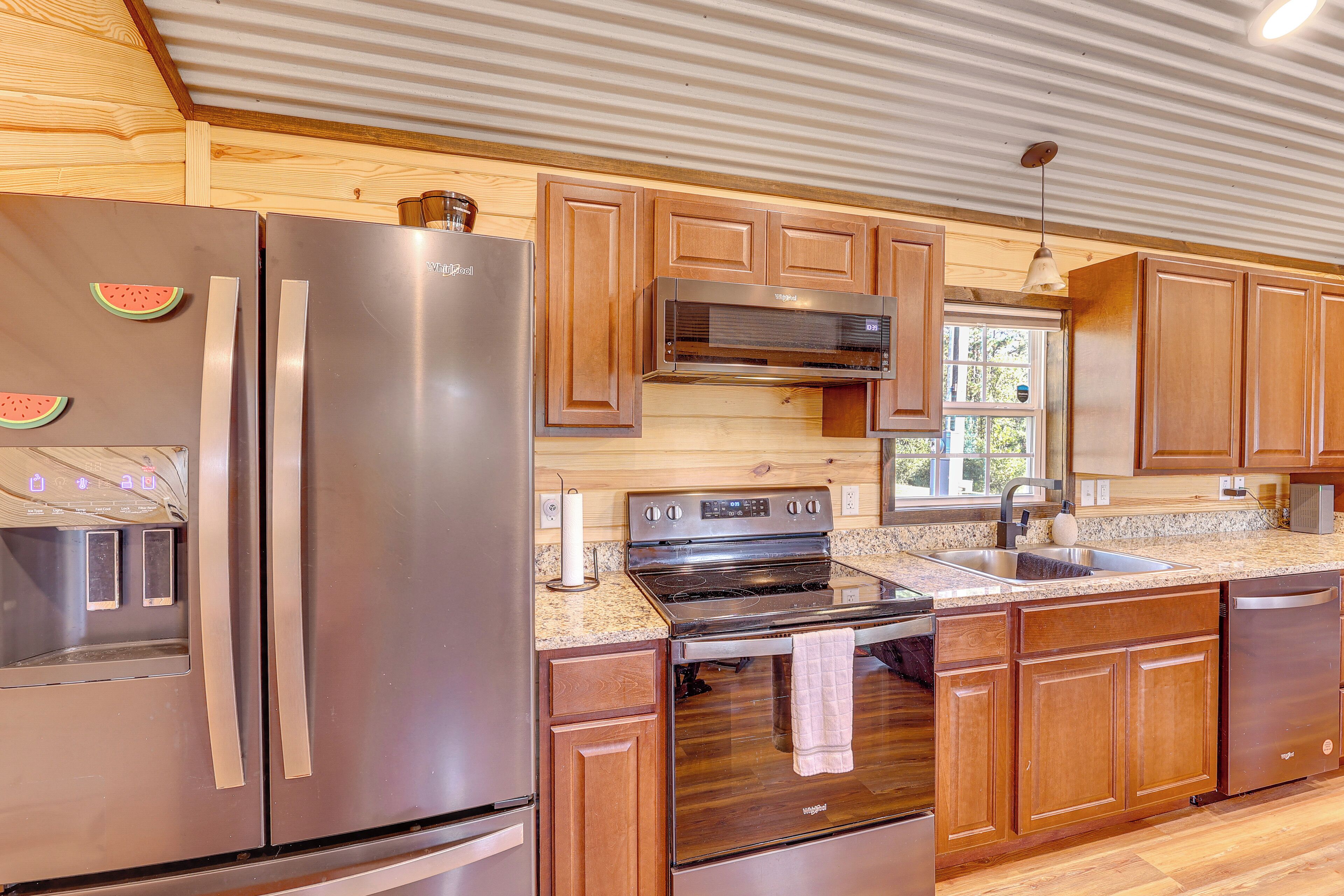 A modern kitchen with stainless steel appliances, wooden cabinets, and a granite countertop.