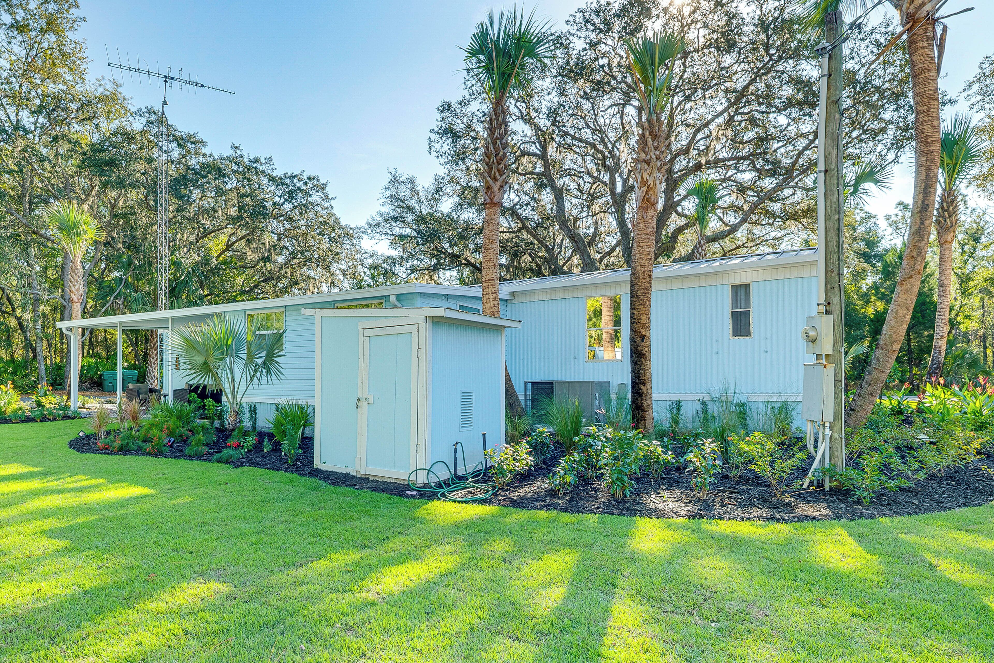 A two-story building with a small attached garage, surrounded by a well-maintained lawn and palm trees.
