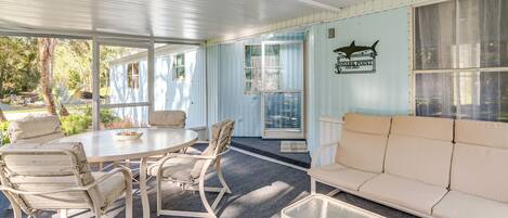 A covered outdoor seating area with a table and chairs, a sofa, and a sign reading "Shark Point."