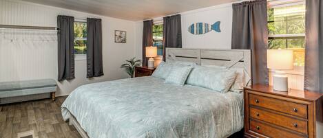 A bedroom with a bed, bedside table, lamp, and a wall-mounted fish decoration.