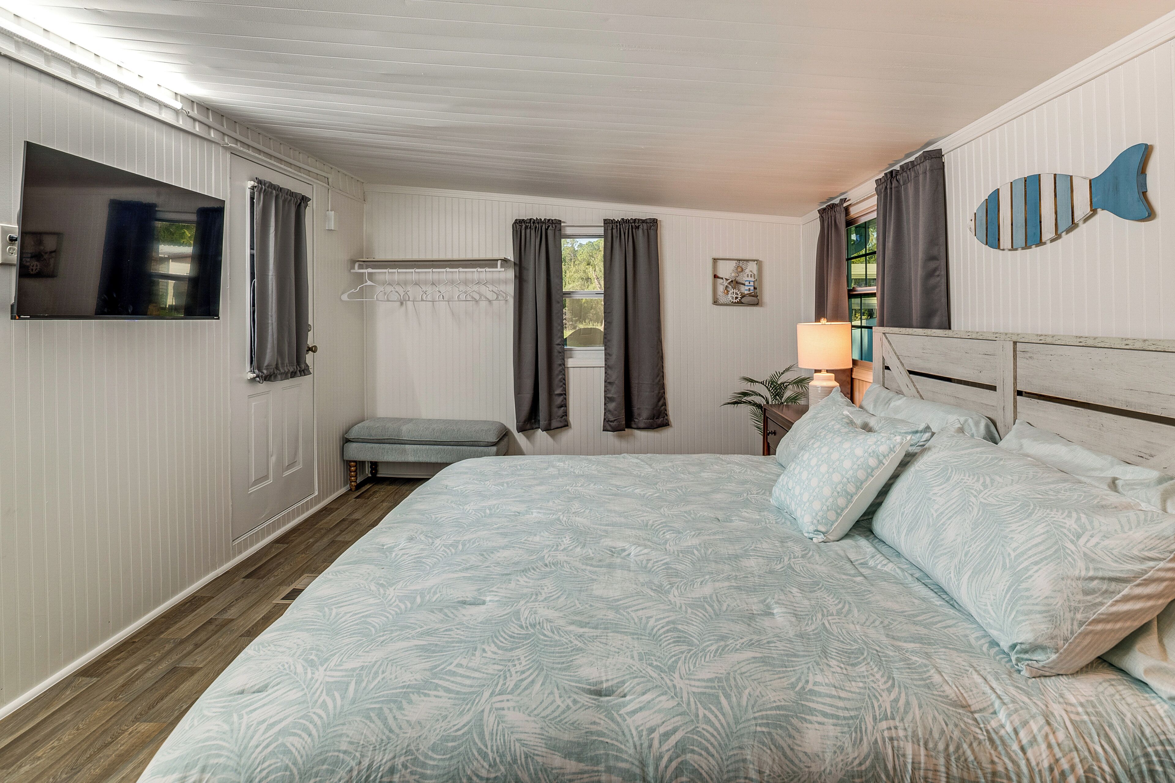 Une chambre à coucher avec un grand lit, une table de chevet avec une lampe, un petit banc et un élément de décoration murale en forme de poisson.
