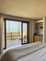 Un dormitorio con una cama grande, un escritorio de madera y vista a la playa.
