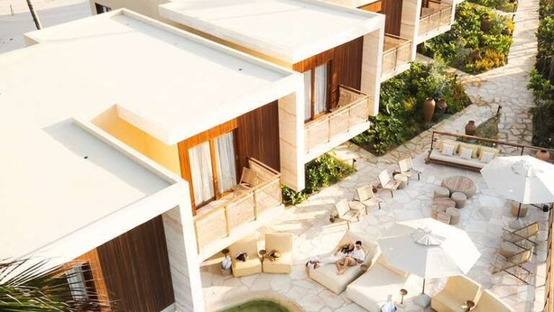 Un hotel moderno con piscina en la azotea, mobiliario exterior y vistas al paisaje desértico.