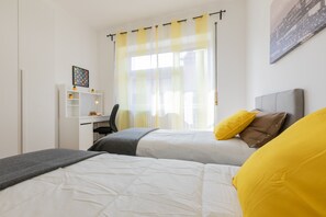 Ett sovrum med två sängar, ett skrivbord och en stol.