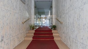 A marble staircase with red carpet leading to a glass elevator. - San Domenico Family Flat by Wonderful Italy (Turin)