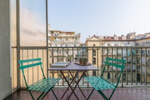 A balcony with a table and two chairs, overlooking a cityscape with buildings. - San Domenico Family Flat by Wonderful Italy (Turin)