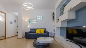 A modern living room with a grey sofa, a white coffee table, and a flat-screen TV. - San Domenico Family Flat by Wonderful Italy (Turin)