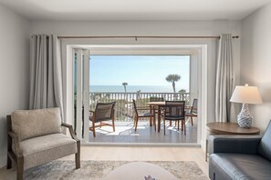 A balcony with a view of the sea, furnished with a table, chairs, and a sofa.
