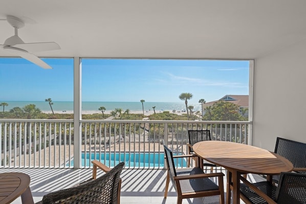 Un balcon avec vue sur une plage et une piscine.
