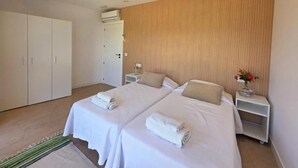 A hotel room with two beds, a wardrobe, a nightstand with a lamp, and a wall-mounted air conditioner. - The tranquility of the mountain near the Miño river. (ARBO)