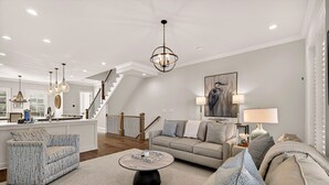 Ein großzügiger Wohnbereich mit Sofa, Ohrensessel und Couchtisch. Eine Treppe führt auf eine obere Ebene.