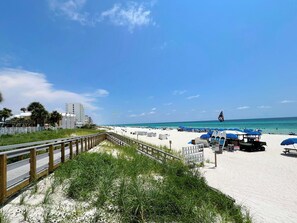 Une plage avec une promenade en bois, des parasols et un poste de surveillance pour les sauveteurs.