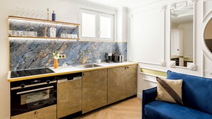 A modern kitchen with a marble backsplash, built-in appliances, and a blue sofa in the adjacent living area.
