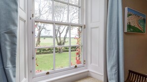 A room with a large window, a bench, and a painting on the wall.