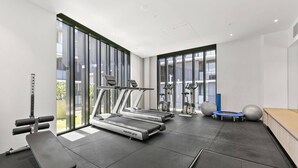 A modern gym with treadmills, a bench press, and exercise balls. - Collingwood Cool 2-bed, Balcony, Gym, Rooftop (Melbourne)
