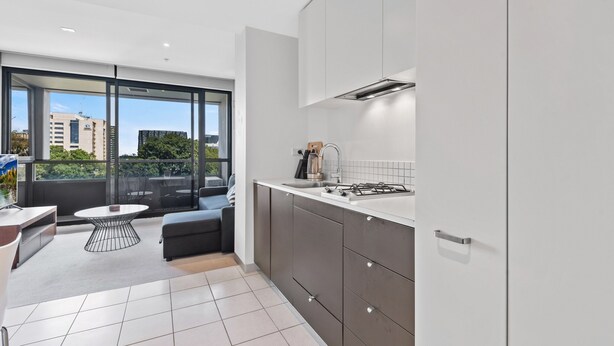 A modern kitchen with a large window, a dining area with a round table, and a sofa. - Central 1-bed Apartment With Secure Parking (Melbourne)