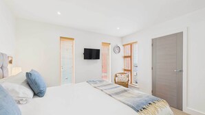 Une chambre à coucher avec un lit, une télévision, une horloge et une porte.