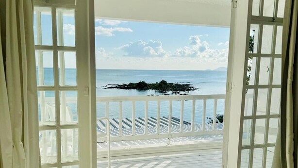 Une chambre avec un lit et une vue sur la mer, grâce à des portes ouvertes.