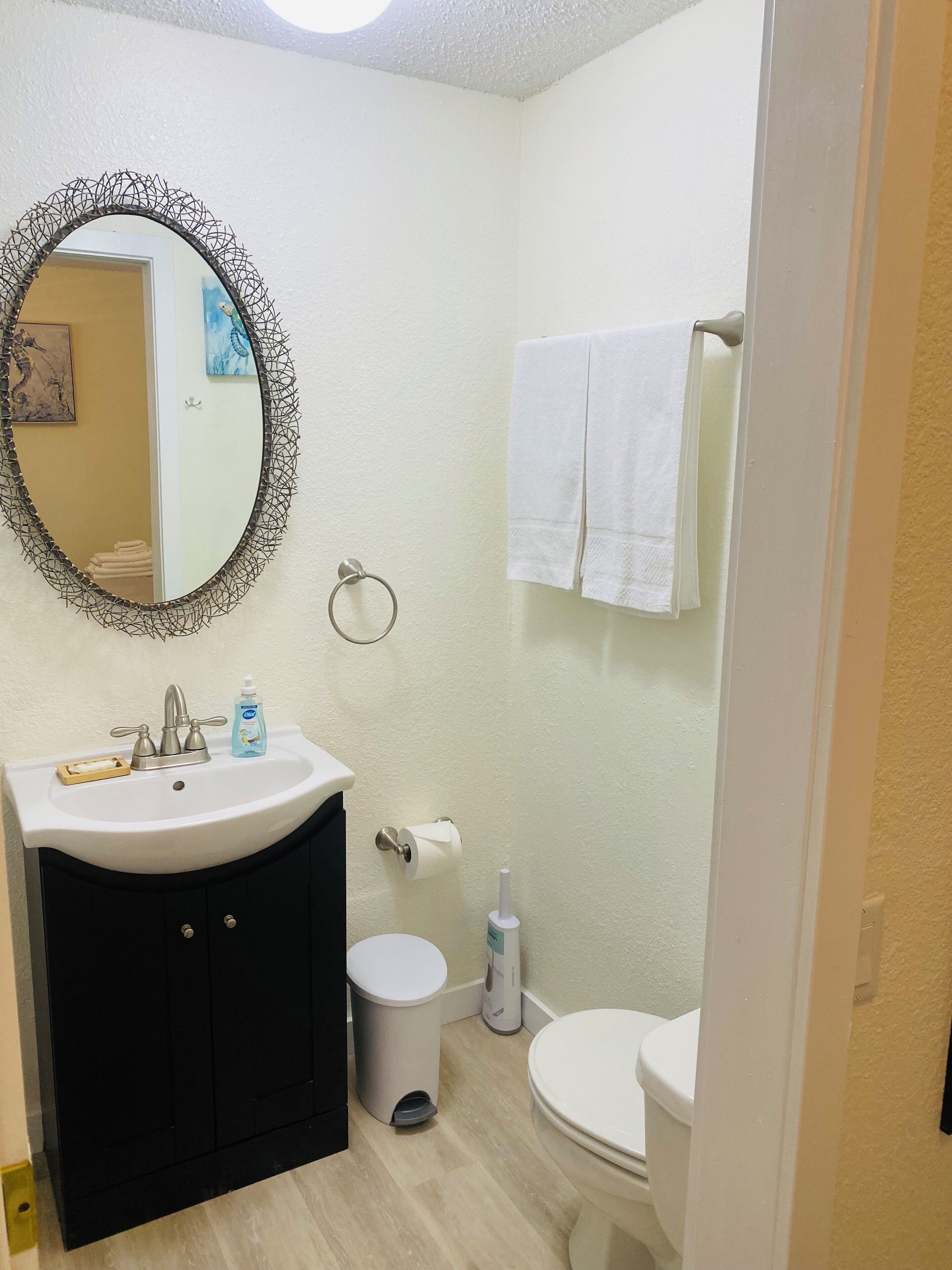 Une salle de bain avec un miroir rond, un lavabo, des toilettes et un porte-serviettes.