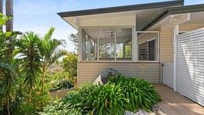 Une maison moderne dotée d’un porche abrité, de grandes fenêtres et d’un jardin bien entretenu.