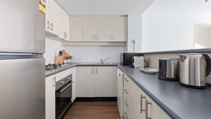 Una cocina moderna con gabinetes blancos, electrodomésticos de acero inoxidable y una encimera negra.