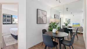 Una habitación de hotel moderna con zona de comedor, un espejo grande y vistas a la ciudad.