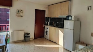 Une petite cuisine fonctionnelle, équipée des appareils électroménagers de base, d’un lave-linge et d’un réfrigérateur.