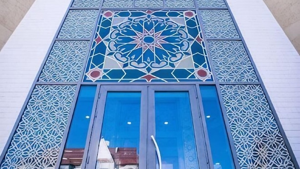 A building facade with intricate geometric patterns and large blue-framed windows. - Shah Palace Hotel (Bishkek)
