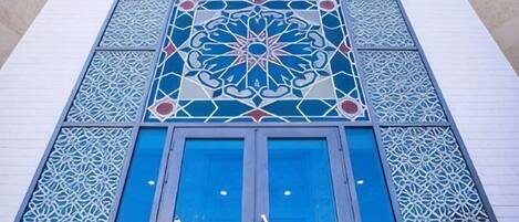 Fachada de edificio con intrincados patrones geométricos y grandes ventanas con marco azul.