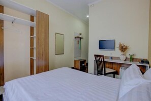 Une chambre d’hôtel équipée d’un lit, d’un bureau, d’une chaise, d’une télévision et d’une armoire.