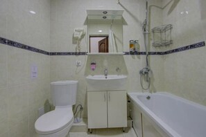 Et badeværelse med toilet, vask og badekar.