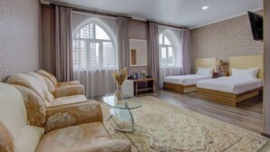 A hotel room with a sofa, two beds, a glass coffee table, and large windows. - Shah Palace Hotel (Bishkek)