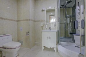 Une salle de bain comprenant des toilettes, un meuble-lavabo et une douche séparée par une paroi en verre.