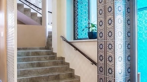 A staircase with marble steps, a handrail, and patterned wall tiles. - Shah Palace Hotel (Bishkek)
