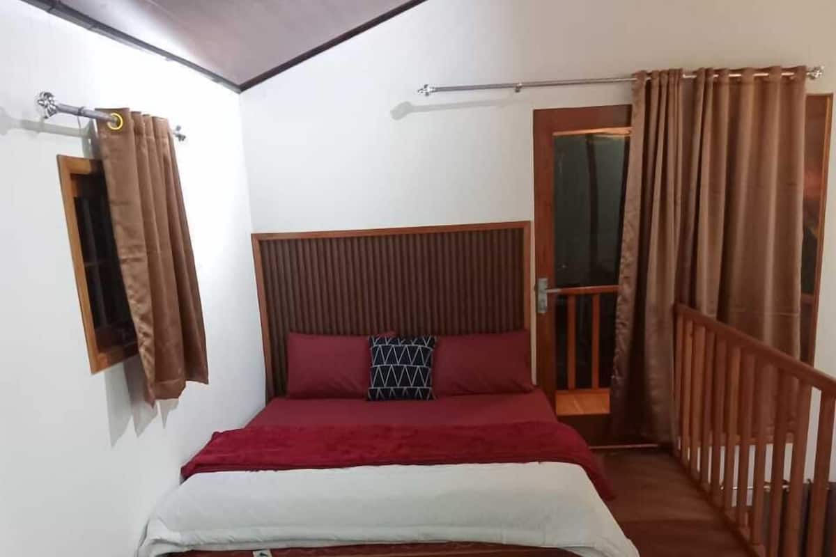 Un dormitorio con una cama, una ventana con cortinas, cabecero de madera y baranda de madera.