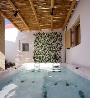 A hot tub with a bamboo ceiling, surrounded by a white wall with a lattice of green vines and white flowers. - Charming House in the Heart of Oia, Private Jacuzzi, Spacious Yard and Kitchen (Oia)