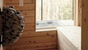 Een houten blokhutinterieur met een groot raam, een ingebouwde bank en een wijnrek aan de muur.