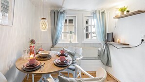 A dining area with a round table, chairs, and a hanging light fixture.