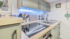 A modern kitchen with a built-in stove, a sink, and a lighted backsplash.