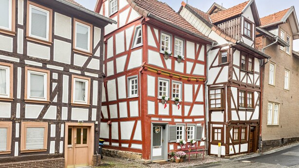 A traditional half-timbered building with a door, windows, and a small porch area.