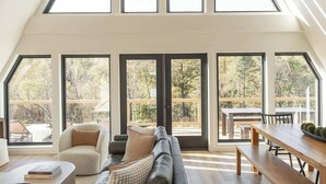 Un loft espacioso con techo alto, ventanas amplias, un sofá modular, una mesa de comedor de madera y una zona de estar acogedora.