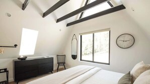Un dormitorio con cama, cómoda, silla, ventana y un reloj de pared.