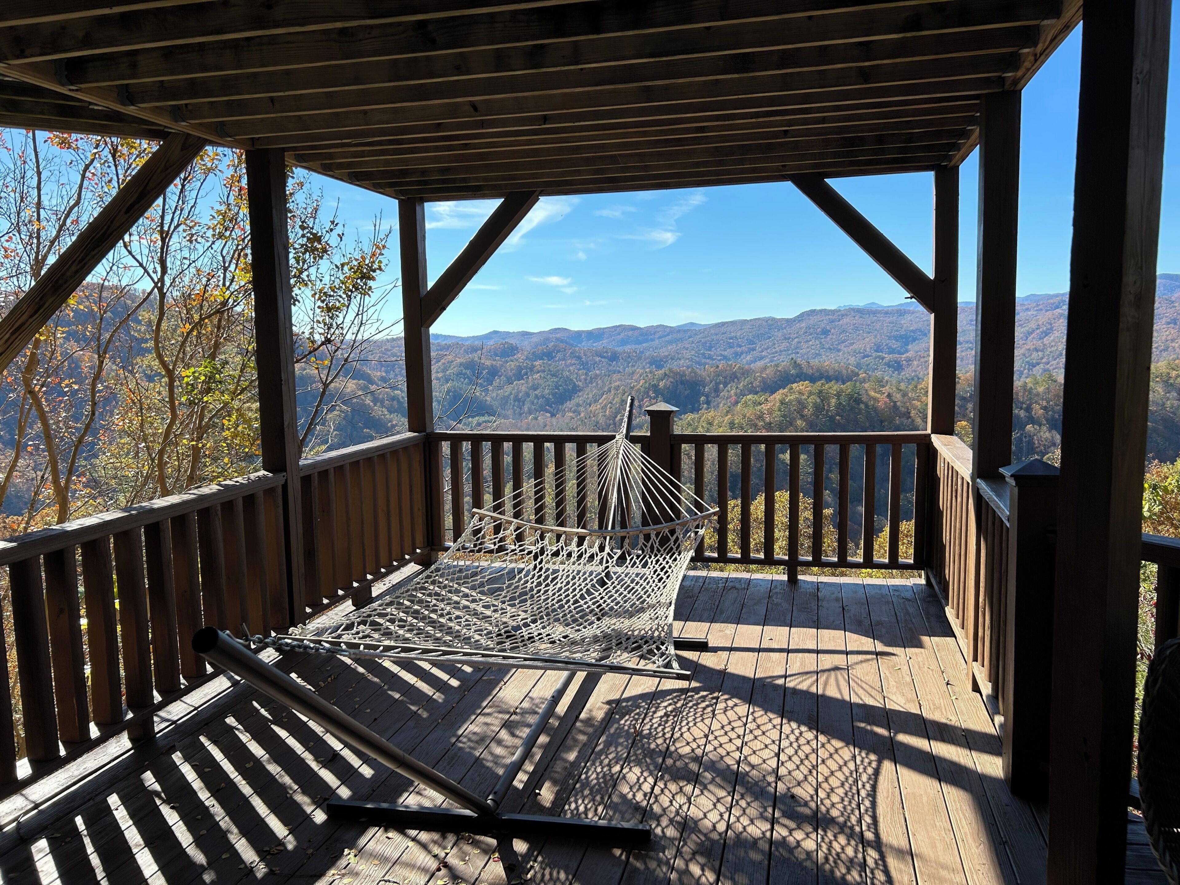 A wooden deck with a hammock and a view of a mountainous landscape.