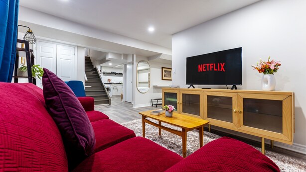 Un salon moderne avec un canapé rouge, une table basse en bois et un téléviseur affichant le logo « NETFLIX ».