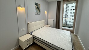 Ein modernes Schlafzimmer mit einem Bett, Nachttischen, einem Heizkörper und einem Fenster mit Vorhängen.